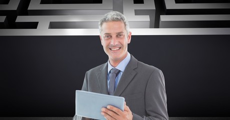 Businessman holding digital tablet while standing against maze