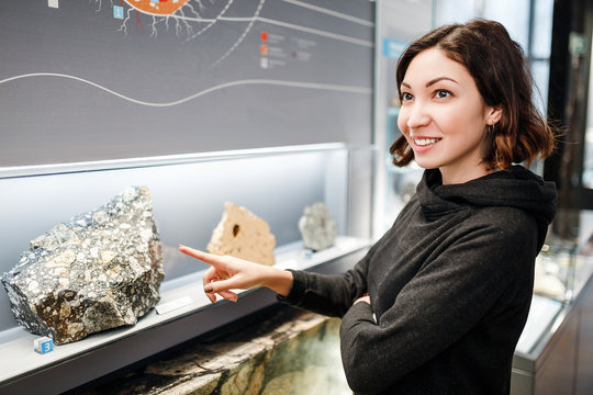 Beautiful Asian happy geologist woman indoors looking at minerals collection, education and science concept