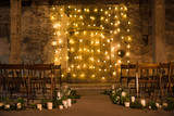 Wedding ceremony decorations in loft grunge surround. Light bulb garland, candles, glass and chairs
