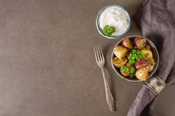 Body multicolored potato baked with herbs and garlic on olive oil, Dark background. Food for a vegan and a vegetarian.