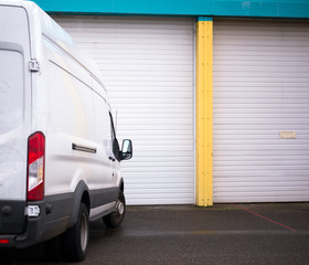 Commercial van for transporting cargo waiting by the warehouse gate