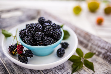 Fresh blackberries in bowl on wooden table. 