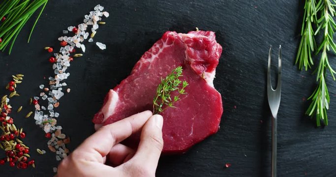 Beautiful juicy fresh meat steak on a table with salt, rosemary, garlic, and tomato on a black background, top view. Concept: fresh & natural products, bio products, meat products, organic, nutrition.