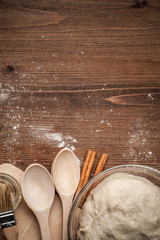 Cooking yeast dough for buns, butter, eggs, cooking equipment, flour on a wooden table. Top view...