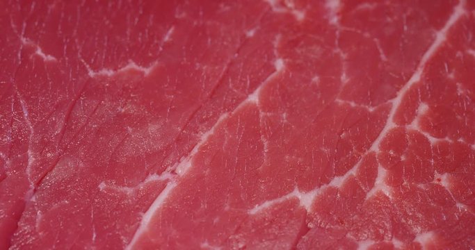Beautiful juicy fresh meat steak on a table with salt, rosemary, garlic, and tomato on a black background, top view. Concept: fresh & natural products, bio products, meat products, organic, nutrition.