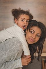 Fototapeta premium little daughter hugging mother while spending time at home