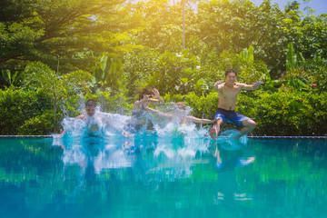 Group Of Friends On Vacation Jumping Into Outdoor Pool