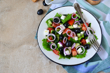 Classic Greek salad with sauce on a concrete background. Greek cuisine.