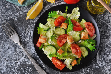 Vegetable salad with cucumber, tomatoes and olive oil on a concrete background