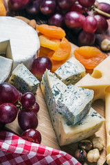 Cheese plate with fruits and nuts on a wooden table