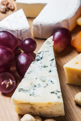 Assorted fresh cheese, fruits and nuts on a wooden table
