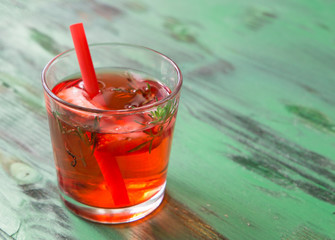 Summer refreshing cocktail with strawberry and thyme on a light green wooden table