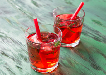 Summer refreshing cocktails with strawberry and thyme on a light green wooden table