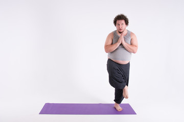 Obraz premium Funny fat man and yoga. Sport, diet and a healthy lifestyle. 