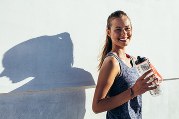 Happy female runner holding water bottle and smiling