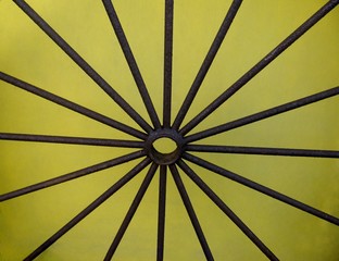 Detail of vintage farm cart wheel on yellow background