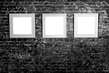 Three empty frames on black brick wall. Blank space posters or art frame waiting to be filled. Square Black Frame Mock-Up