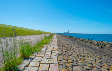 Dike of basalt stones along a lake in spring