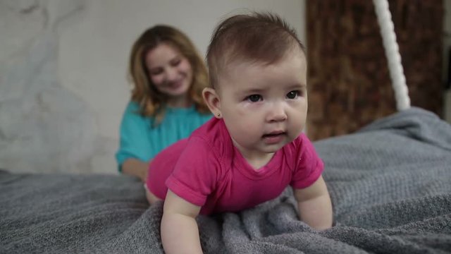Adorable baby girl learning to crawl on bed