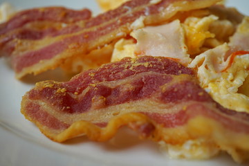 Macro detail of a typical English and American breakfast made of crispy bacon strips and scrambled eggs 