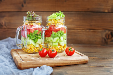 Glass jars with vegetable salad, cherry tomatoes and sunflower seeds. Top view. Healthy food, Diet, Detox, Clean Eating or Vegetarian concept