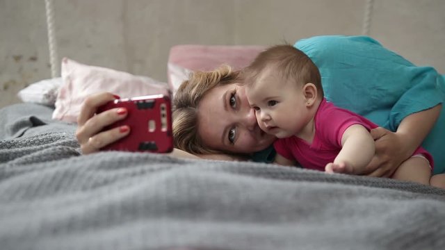 Mother and baby taking selfie with phone in bed