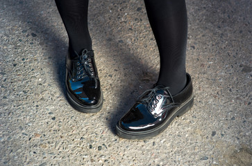 Beautiful young female legs in black elegant shoes on asphalt