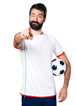 Football player holding a soccer ball pointing to the front