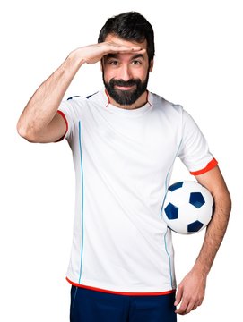 Football player holding a soccer ball showing something