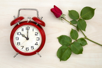Love concept - red rose and a vintage alarm clock