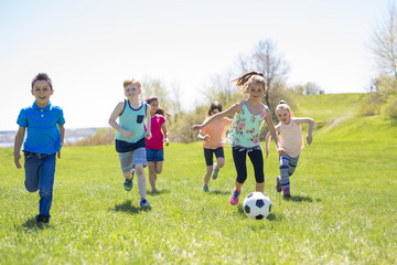 Obraz na płótnie Canvas Boys and girls running towards football