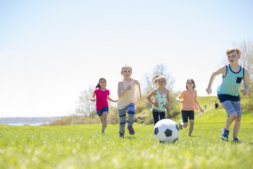 Obraz na płótnie Canvas Boys and girls running towards football