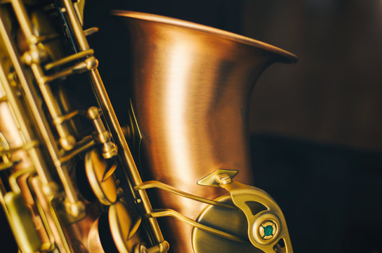 Detail of alto saxaphone, over black background.