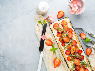 Home made strawberry not baked cheese cake in oven tin on gray background with flowers