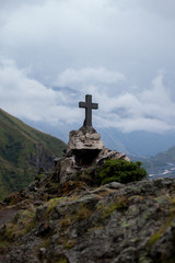 Orthodox cross near Caucasus mountains. Cloud sky background