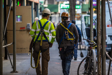 Two construction workers walk together down a New York City sidewalk