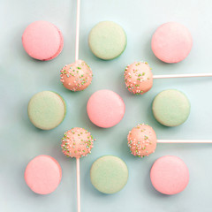 Fototapeta na wymiar Mint and strawberry flavor macarons and cake pops on sticks. Flat lay. Top view