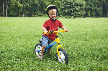 Happy toddler child boy riding bike without pedals. Kids enjoying a bicycle ride. Sport concept. Kids ride bicycle. First bike for little children. Active toddler kid playing and cycling outdoors.