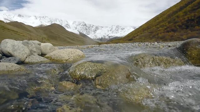 Amazing touristic place near river in mountain valley at the foot of Mt. Shkhara 5,193 m (17,040 ft). Upper Svaneti, Georgia, Europe. Caucasus mountains. HD video clip (High Definition).