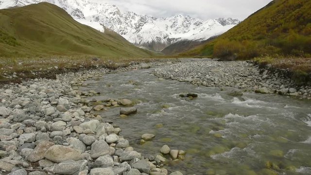 Amazing touristic place near river in mountain valley at the foot of Mt. Shkhara 5,193 m (17,040 ft). Upper Svaneti, Georgia, Europe. Caucasus mountains. HD video clip (High Definition).