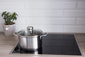 cooking concept - close up of metal pot on electric or induction stove in kitchen - obrazy, fototapety, plakaty