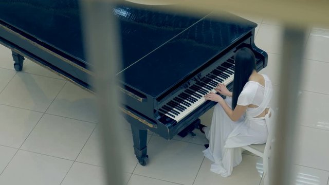 Shooting from the above of the girl playing the piano. No face. 4K.