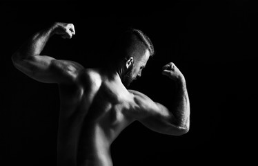 Obraz na płótnie Canvas The back view torso of attractive male body builder on black background.