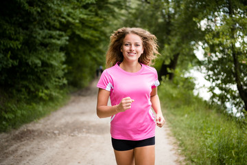 Young fitness woman running through the forest