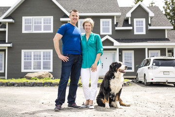 Cheerful couple standing in front of new house