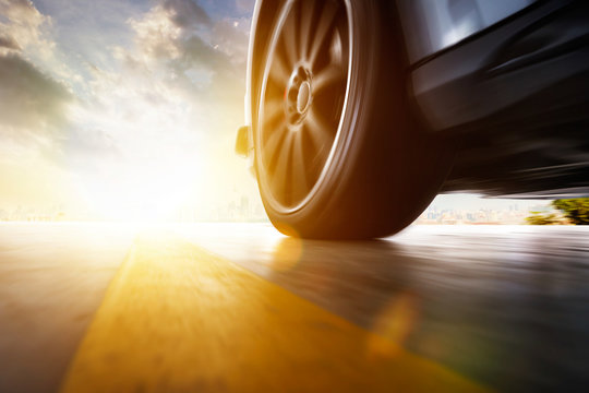 Low Angle Side View Of Car Driving Fast At Sunset With Motion Speed Effect .