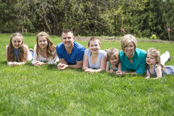 Fototapeta premium Happy family members lay in green grass outdoors