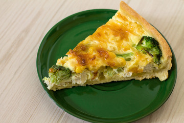 Traditional French quiche Lorraine with chicken, egg, milk, cheese broccoli and corn on a wooden background.