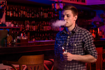 The man smoke an electronic cigarette at the vape shop.