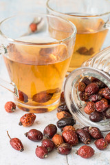   Dry fruit rose hips.  Freshly prepared infusion of dry fruit rose hips in glass transparent mug on a light wooden background.